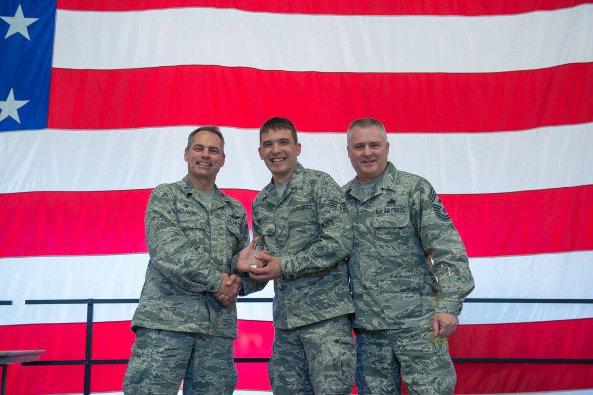 Senior Airman Tyler Kruger receives the Airman of the Quarter award from Col. Tony Polashek, 934th Airlift Wing commander, and Chief Master Sgt. Anthony Mack, 934 AW command chief at the wing commander's call Nov. 5.