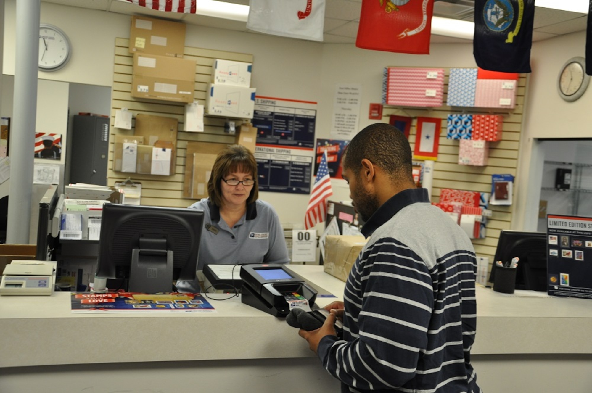Kathy Kimmey, lead sales service associate at the Kittyhawk Post Office, helps Michael Tummings with postage. (U.S. Air Force photo/W. Eugene Barnett Jr.)