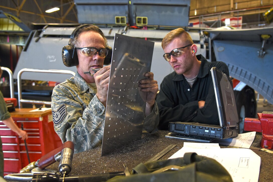 Tech. Sgt. Steven Olander, 141st Maintenance Squadron aircraft structural maintenance technician, and Senior Airman Logan Lingren, 92nd MXS aircraft structural maintenance technician, create a sidewall skin for the left landing gear wheel well Nov. 15, 2016, at Fairchild Air Force Base. The skin replaced a portion of metal in the left landing gear wheel well affected by corrosion. (U.S. Air Force photo/Senior Airman Mackenzie Richardson)