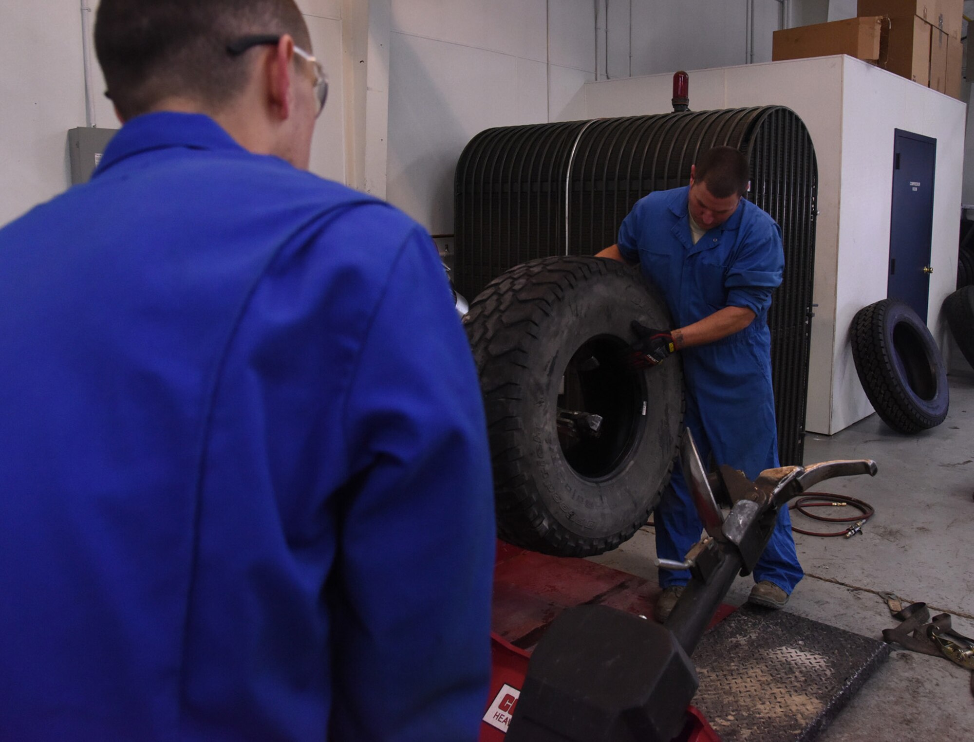 Airman 1st Class Johnathan Allen, left, 341st Logistics Readiness Squadron vehicle maintenance apprentice, and Technical Sgt. Gregory Cornelison, right, NCO in charge of mobile maintenance, pull a tire off a large tire machine at the LRS tire shop Nov. 29, 2016, at Malmstrom Air Force Base, Mont. Damaged tires are rolled to the back onto a trailer to take to disposition. (U.S. Air Force photo/Senior Airman Jaeda Tookes)