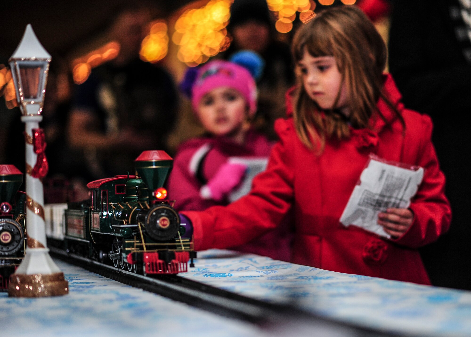 Children watch a model train pass by during the Starry, Snowy, Southwest Night holiday celebration at Davis-Monthan Air Force Base, Ariz., Dec. 1, 2016. Desert Lightning Team members and their families were invited to enjoy free hot chocolate and cookies while participating in festivities such as photos with Santa, a giant rocking horse, a mechanical snowboard, arts and crafts and much more. (U.S. Air Force photo by Airman Nathan H. Barbour)