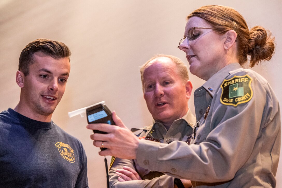 Airman 1st Class Kaleb Marquis, 775th Explosive Ordnance Disposal Flight, reacts to his breathalyzer reading during a DUI and distracted driving event Dec. 2 at Hill Air Force Base. Lt. Susan Poulsen administered the test to Marquis, who had consumed five 12-ounce beers. Also pictured is Davis County Undersheriff Brent Peters. (U.S. Air Force photo by Paul Holcomb)