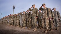 A formation of Army explosive ordnance disposal students salute during base retreat at Eglin Air Force Base, Fla, Dec. 1.  A few of the soldiers donned Santa hats and held toys to be delivered to the base’s toy drive.  After Retreat, the formation marched over to Bldg. 615 to drop off the toys.  (U.S. Air Force photo/Samuel King Jr.)