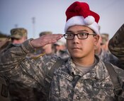 A private 1st class in a Santa hat salutes during base retreat at Eglin Air Force Base, Fla, Dec. 1.  A few of the Army explosive ordnance disposal students donned Santa hats and held toys to be delivered to the base’s toy drive.  After Retreat, the formation marched over to Bldg. 615 to drop off the toys.  (U.S. Air Force photo/Samuel King Jr.)