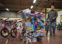 A parent chooses a bike to go along with his full shopping cart of gifts during the base’s annual toy drive at Eglin Air Force Base, Fla., Dec. 2. Approximately 2,000 toys were collected by donations made throughout the year. Toys, bikes, books, games, crafts, sports equipment and stuffed animals were given to active-military families in need of assistance during the holidays. (U.S. Air Force photo/Samuel King Jr.)