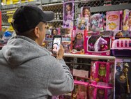 A parent uses “facetime” to show his spouse gifts and talk about what to grab during the base’s annual toy drive at Eglin Air Force Base, Fla., Dec. 2. Approximately 2,000 toys were collected by donations made throughout the year. Toys, bikes, books, games, crafts, sports equipment and stuffed animals were given to active-military families in need of assistance during the holidays. (U.S. Air Force photo/Samuel King Jr.)