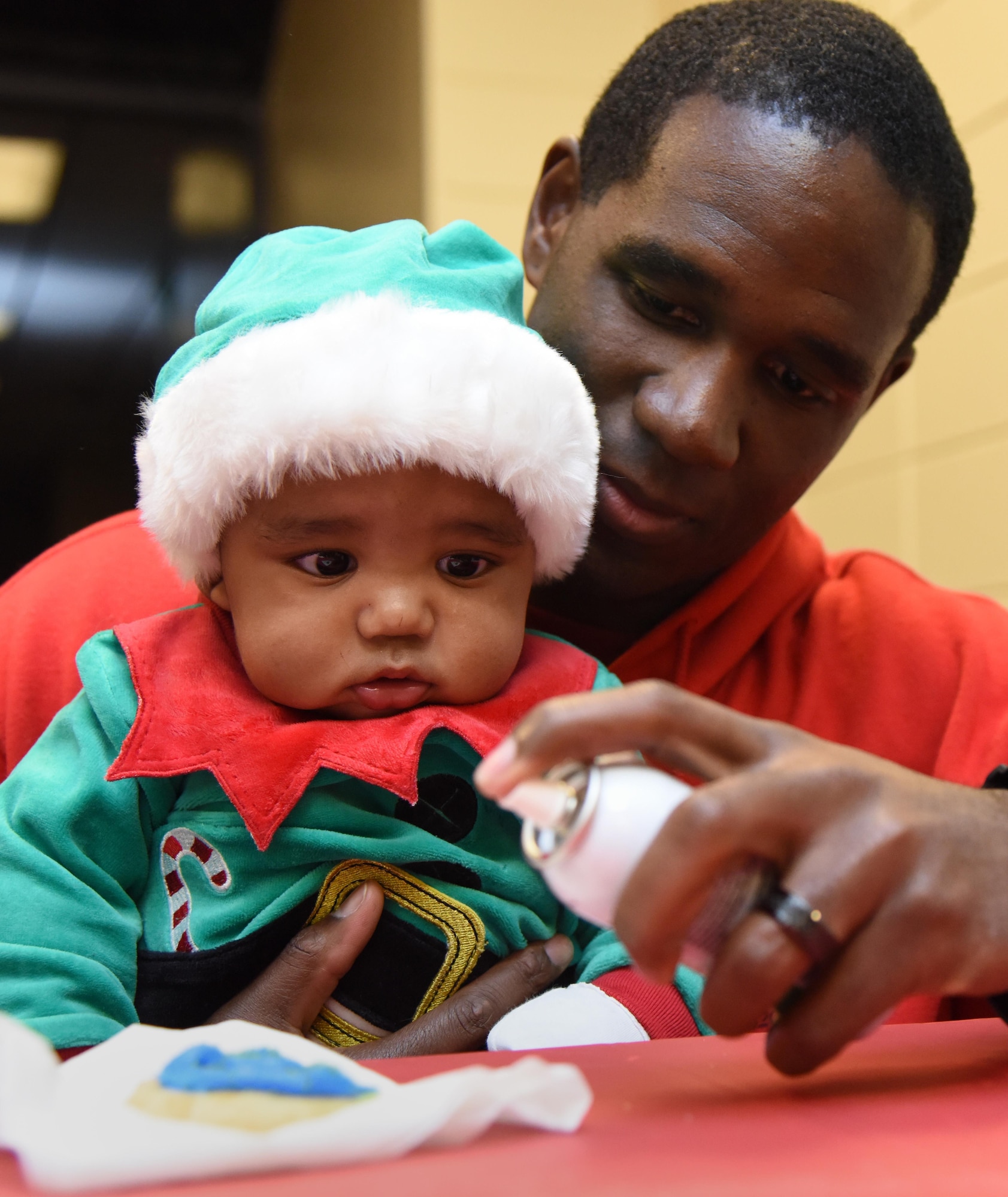 Airman 1st Class, Rapheal Davis, 403rd Wing aerospace medical technician, helps his son, Ayden, decorate a cookie during Keesler’s annual Christmas in the Park celebration at Marina Park Dec. 1, 2016, on Keesler Air Force Base, Miss. The event, hosted by Outdoor Recreation, also included a tree lighting ceremony, tour train rides, ornament decorating, and visits with Santa. (U.S. Air Force photo by Kemberly Groue)
