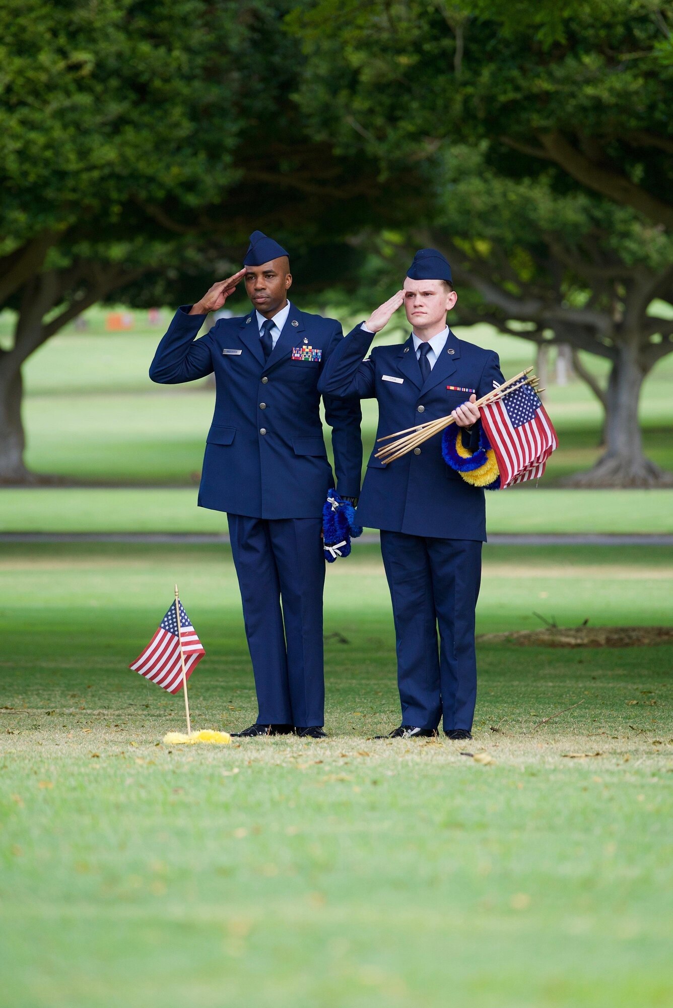 U.S. Air Force Staff Sgt. Johnnie Anderson and Airman 1st Class Andrew Titus, dental technicians with the 15th Aeromedical Squadron, salute a fallen U.S. servicemember's  gravemarker at the National Memorial Cemetery of the Pacific, Honolulu, Hawaii, Dec. 3, 2016. Anderson and Titus placed multiple flags during a commemoration ceremony honoring the courage, service and sacrifice of the U.S. military personnel who died during the attacks on Pearl Harbor and Oahu on Dec. 7, 1941. Dec. 7, 2016 marks the 75th anniversary of the attacks and the U.S. military and the State of Hawaii are hosting a series of remembrance events to honor the Pacific Theater's veterans. (U.S. Air Force photo by Tech. Sgt. James Stewart/Released)