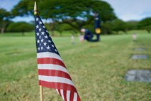 In the distance, U.S. Air Force Staff Sgt. Johnnie Anderson and Airman 1st Class Andrew Titus, dental technicians with the 15th Aeromedical Squadron, place a commemorative U.S. flag at a gravemarker at the National Memorial Cemetery of the Pacific, Honolulu, Hawaii, Dec. 3, 2016. Anderson and Titus placed multiple flags during a commemoration ceremony honoring the courage, service and sacrifice of the U.S. military personnel who died during the attacks on Pearl Harbor and Oahu on Dec. 7, 1941. Dec. 7, 2016 marks the 75th anniversary of the attacks and the U.S. military and the State of Hawaii are hosting a series of remembrance events to honor the Pacific Theater's veterans. (U.S. Air Force photo by Tech. Sgt. James Stewart/Released)
