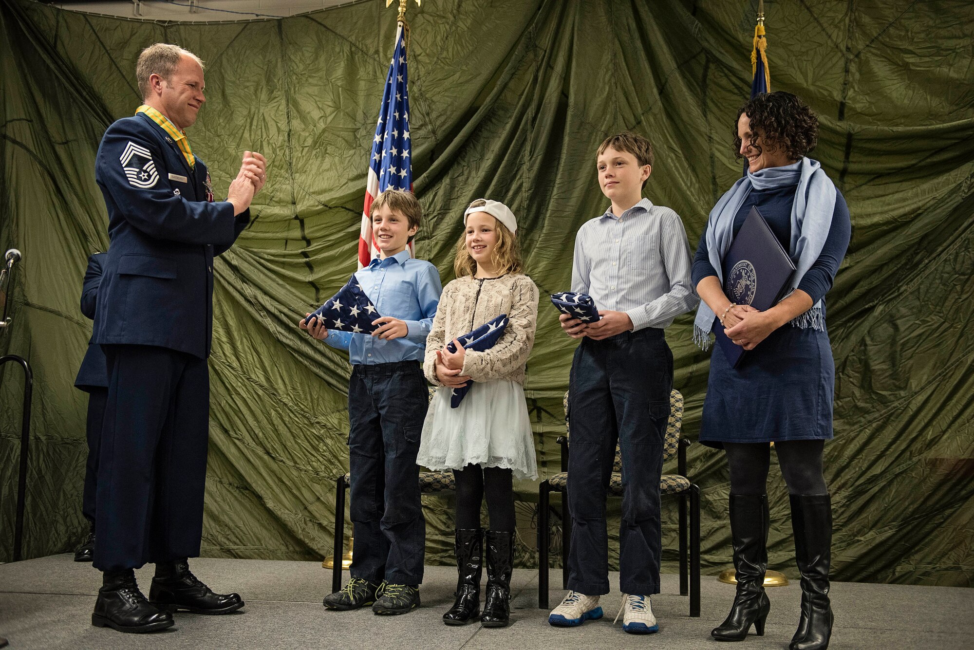 JOINT BASE ELMENDORF-RICHARDSON, Alaska -- Chief Master Sgt. Paul Bear Barendregt, a pararescueman and chief enlisted manager for the Alaska Air National Guard's 212th Rescue Squadron, applauds after presenting his three children with American flags during his retirement ceremony at the 212th's headquarters building here Dec. 3, 2016. Through his skill and commitment Barendregt exemplified the motto of the Air Force Pararescueman: These things we do, that others may live. (U.S. Air National Guard photo by Staff Sgt. Edward Eagerton/released)