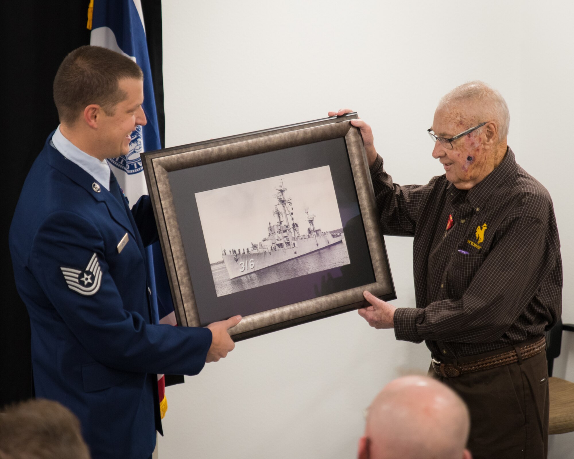 U.S. Air Force Tech. Sgt. Bryce Bishop and his grandfather, Kenneth Murphy, pose for a picture during a medal presentation ceremony, Dec. 3, 2016 at Cheyenne Air National Guard base in Cheyenne, Wyoming. Murphy was awarded the Ambassador for Peace Medal for his service aboard the USS Harveson (DE) as a U.S. Navy gunners mate during the Korean War. (U.S. Air National Guard photo by Tech. Sgt. John Galvin/released)