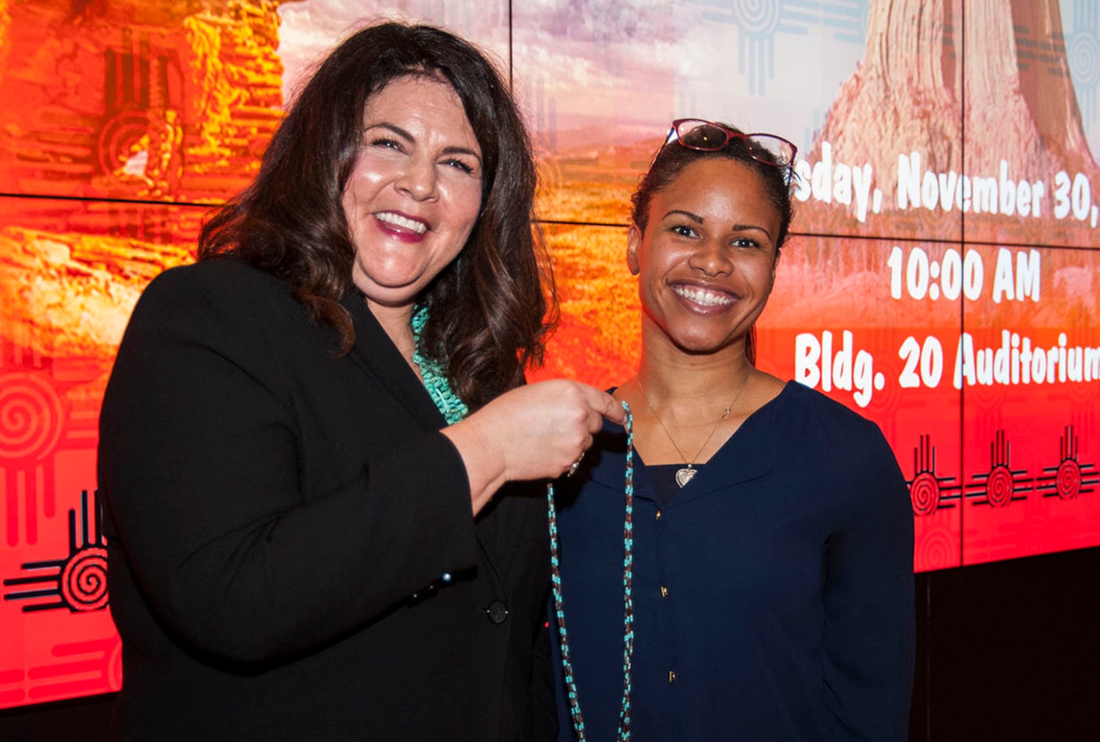 Stacey Halfmoon (left), director of American Indian Relations for the Ohio History Connection, holds a hand-woven turquoise necklace presented to her by Caroline Watson (right), chair of DLA Land and Maritime’s Equal Employment Opportunity Native American Special Emphasis Program, on behalf of the Defense Federal Community. The "give-away" presentation came at the end of DSCC's National American Indian History Month observance Nov. 30.  