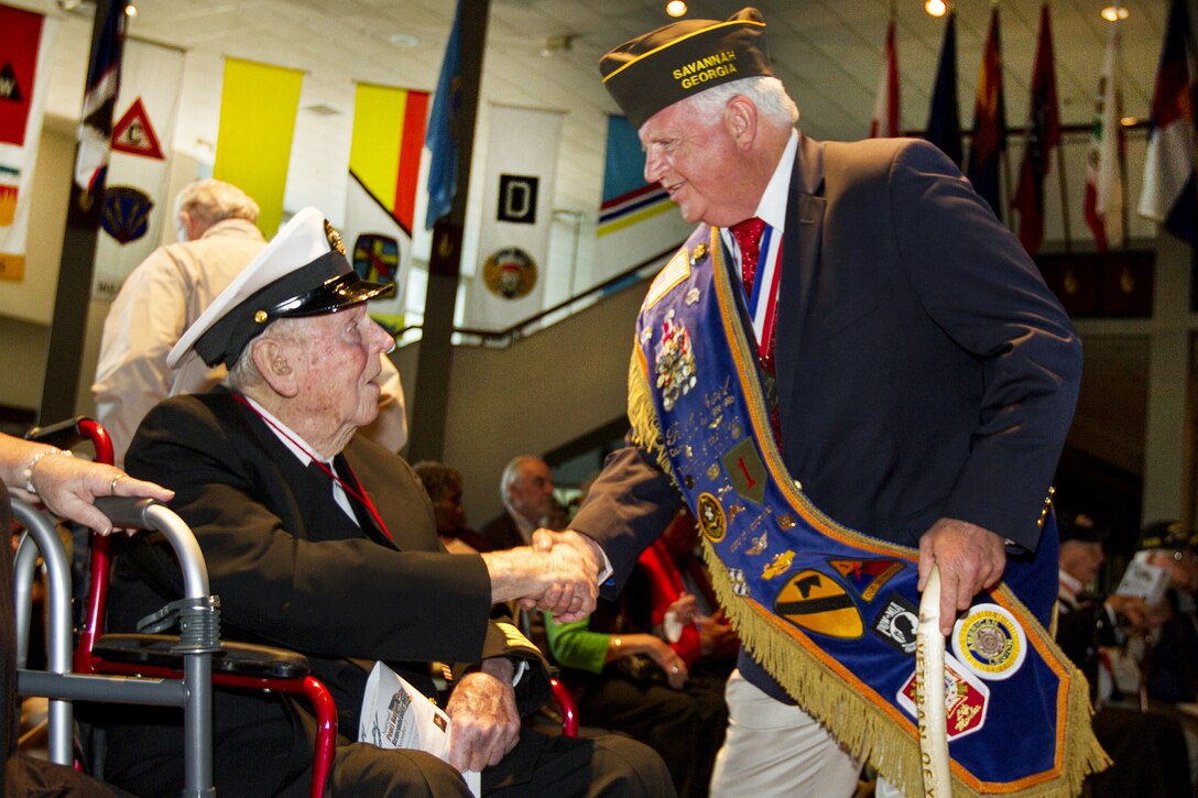 Retired Navy Chief Petty Officer Glover Manning, left, who was an engineman aboard the USS Rigel during the Pearl Harbor attack, shakes hands with Retired Army Col. Rich Noel at the National Museum of the Mighty Eighth Air Force in Pooler, Georgia, Dec. 4, 2016. Army photo by Spc. Scott Lindblom