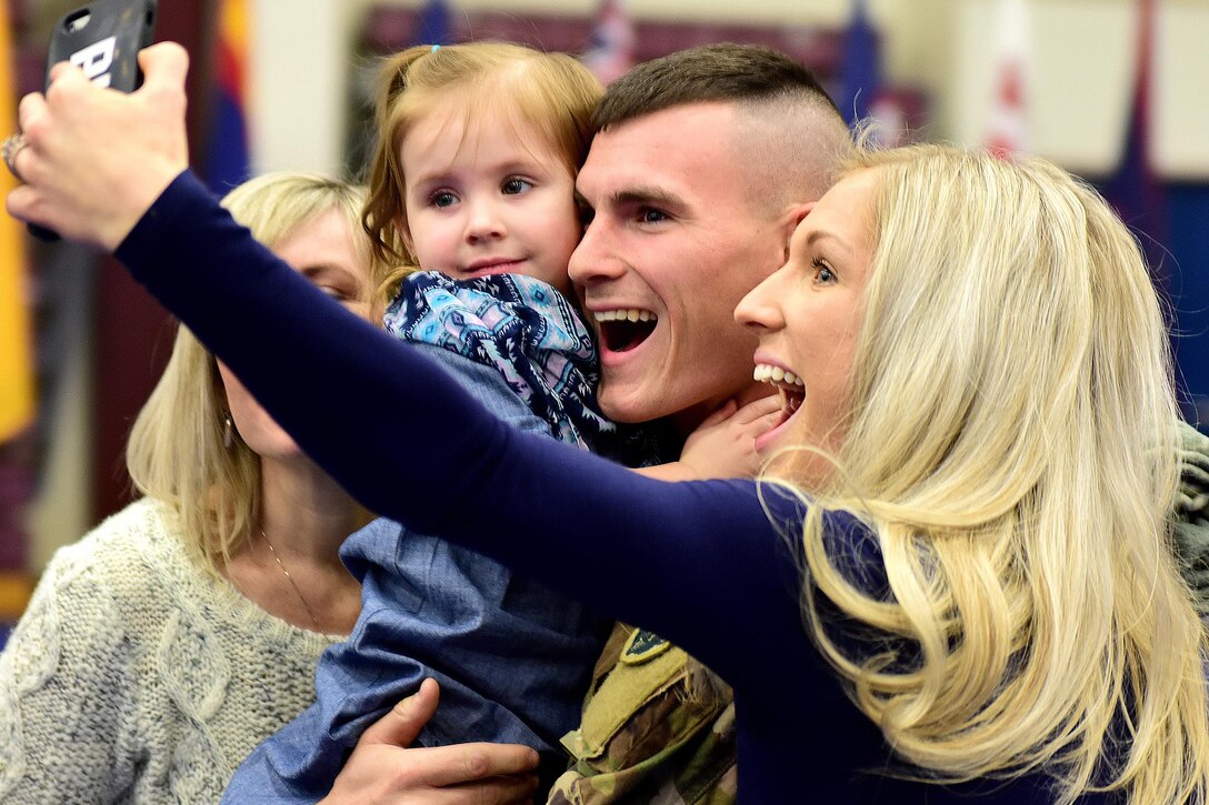 Army Sgt. Matthew Brock poses for a family reunion photo after a welcome home ceremony at the Buckner Physical Fitness Center, Joint Base Elmendorf-Richardson, Alaska, Dec. 1, 2016. Brock is assigned to the 109th Transportation Company, 17th Combat Sustainment Support Battalion, and was returning from a deployment to Kuwait. Army photo by John Pennell