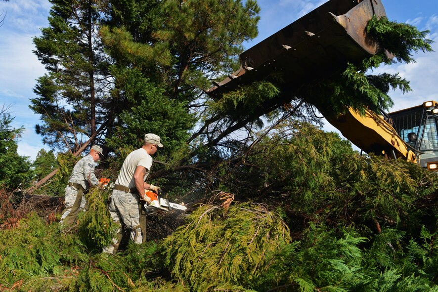 From left, U.S. Air Force Staff Sgt. Sonny Tanner and Senior Airman Reid Johanns, 20th Civil Engineer Squadron heavy equipment craftsman and journeyman respectively, use chainsaws to cut trees while U.S. Air Force Staff Sgt. Claudas Crenshaw, 20th CES heavy equipment journeyman, operates a front-end loader to pick up the debris at Shaw Air Force Base, S.C., Dec. 5, 2016. The heavy equipment flight has cleaned up approximately 300 trees around Shaw that were damaged or uprooted during Hurricane Matthew. (U.S. Air Force photo by Airman 1st Class Destinee Sweeney)