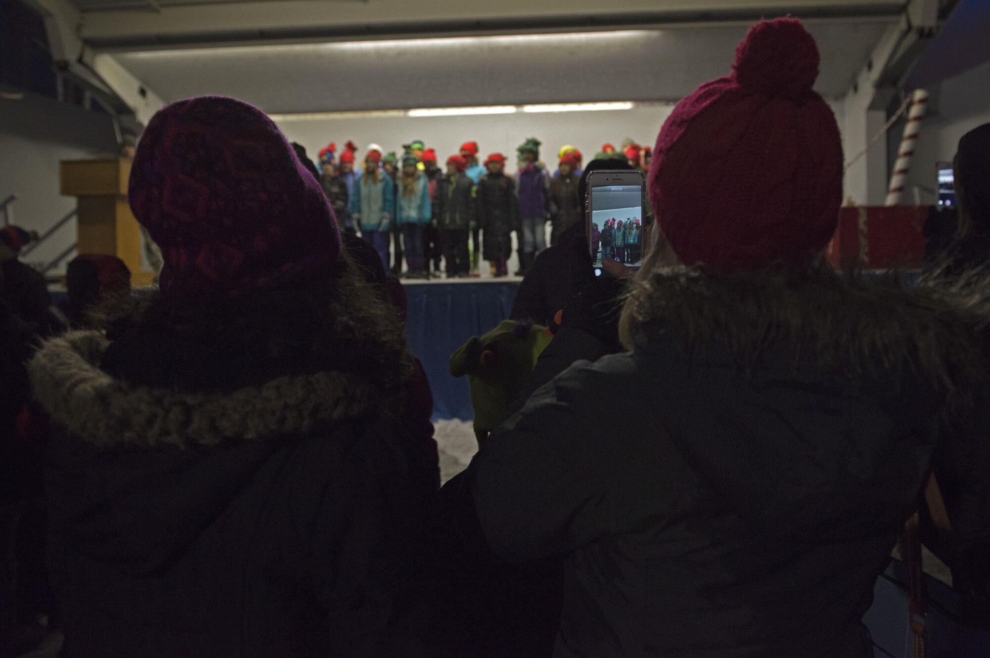 Service members and families watch the Ursa Major Elementary School choir sing Christmas songs during the annual Joint Base Elmendorf-Richardson Holiday Tree Lighting, at JBER, Alaska, Dec. 1, 2016. The annual event brings service members, families, and wing leadership to begin the holiday season.