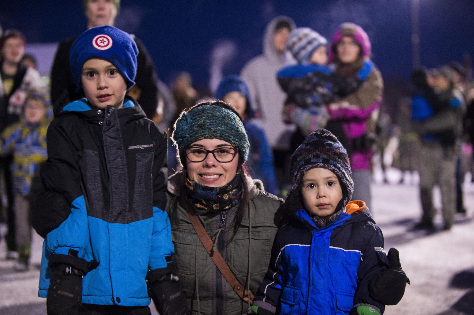 Beatriz Rappisi and her two boys, Domenic, 6, and Lucas, 2, pose for the camera while listening to the Ursa Major Elementary School choir during the annual Joint Base Elmendorf-Richardson Holiday Tree Lighting, Dec. 1, 2016. Service members and families gathered together to see the Holiday Tree lights up. 