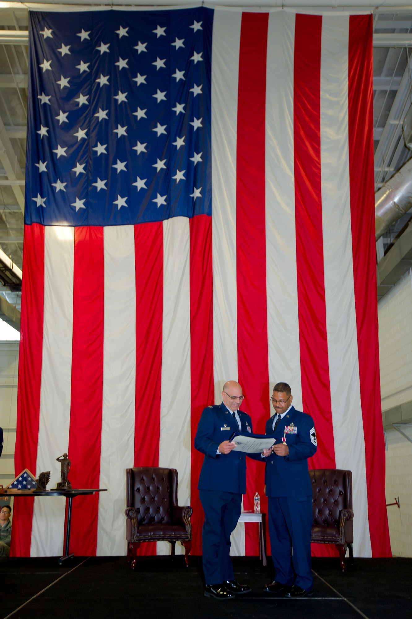 Col. Anthony Esposito, 514th Maintenance Group commander, and Chief Master Sgt. Dennis Christian, 714th Aircraft Maintenance Squadron maintenance superintendent, read over a letter of appreciation from President Barak Obama, during Christian's retirement ceremony Dec. 3.