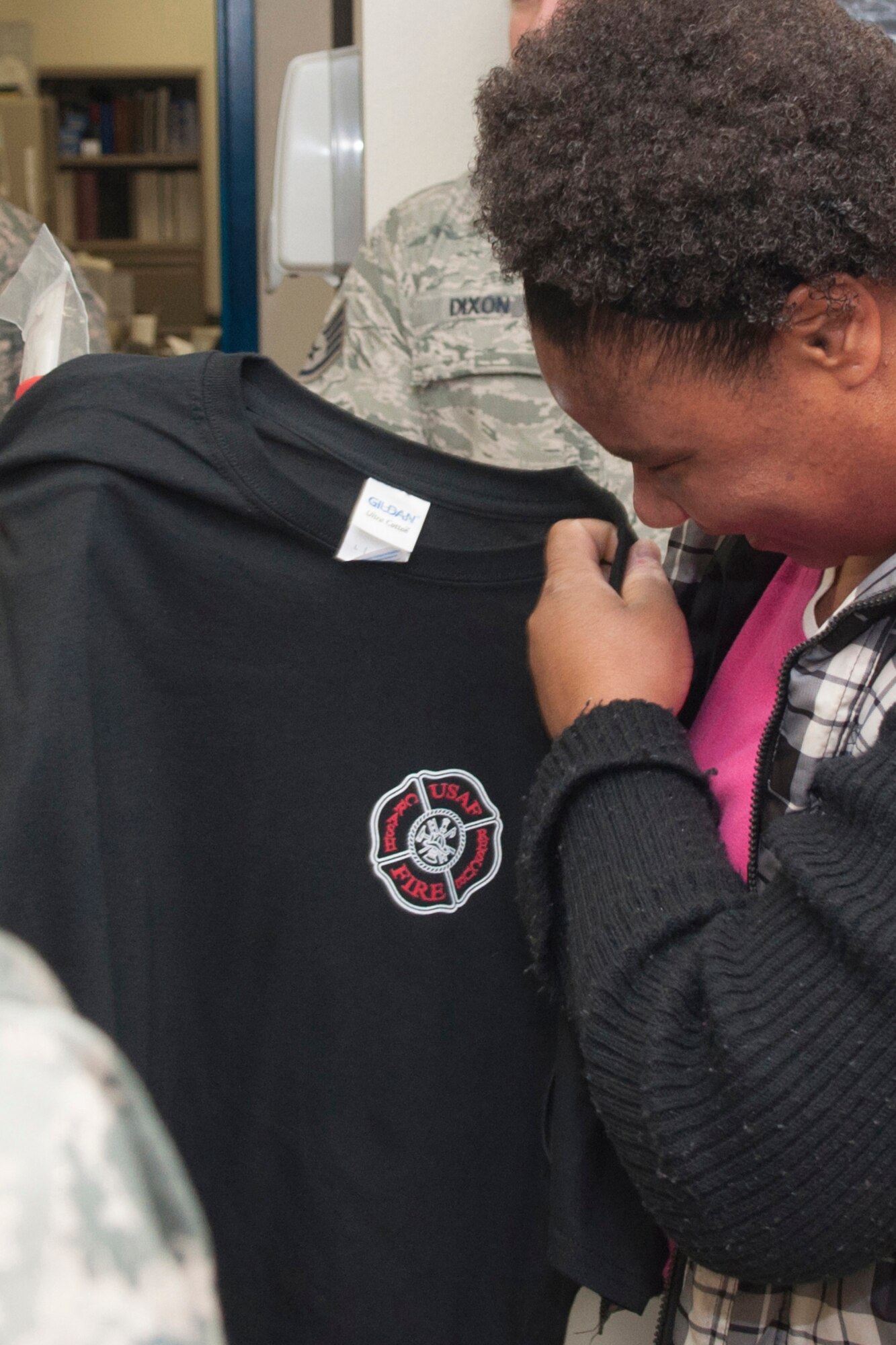 U.S. Air Force Senior Airman Ramona Gilmer, 307th Medical Squadron health services attendant, looks over a morale shirt from the 307th Civil Engineering Squadron firefighters at Barksdale Air Force Base, La., Dec. 4, 2016.   The firefighter presented her the shirt and a gift certificate as part of an annual program to recognize Airman that go above and beyond to help others.   Gilmer recently made extraordinary sacrifices to help several family members who were in crisis. (U.S. Air Force photo by Tech. Sgt. Cody Burt/released). 