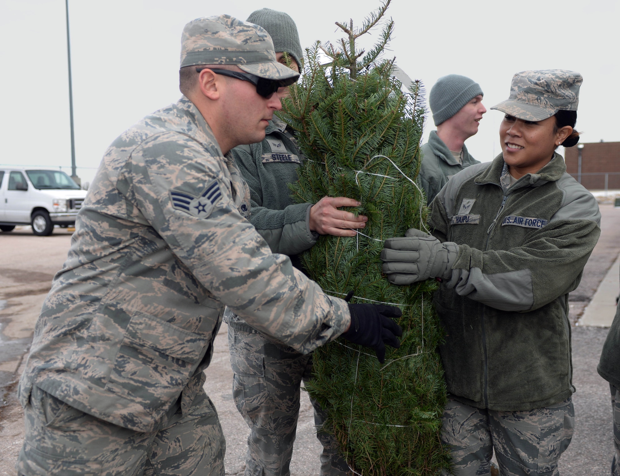 Airman 1st Class Holly Haupu, a lodging apprentice assigned to the 28th Force Support Squadron, passes a Christmas tree down a line during Ellsworth’s ninth annual Trees for Troops event outside the Outdoor Recreation Center at Ellsworth Air Force Base, S.D., Dec. 2, 2016. This national program started with a simple idea of tree farmers wanting to find a way to give back to our nation’s military service members. (U.S. Air Force photo by Airman 1st Class Denise M. Jenson)