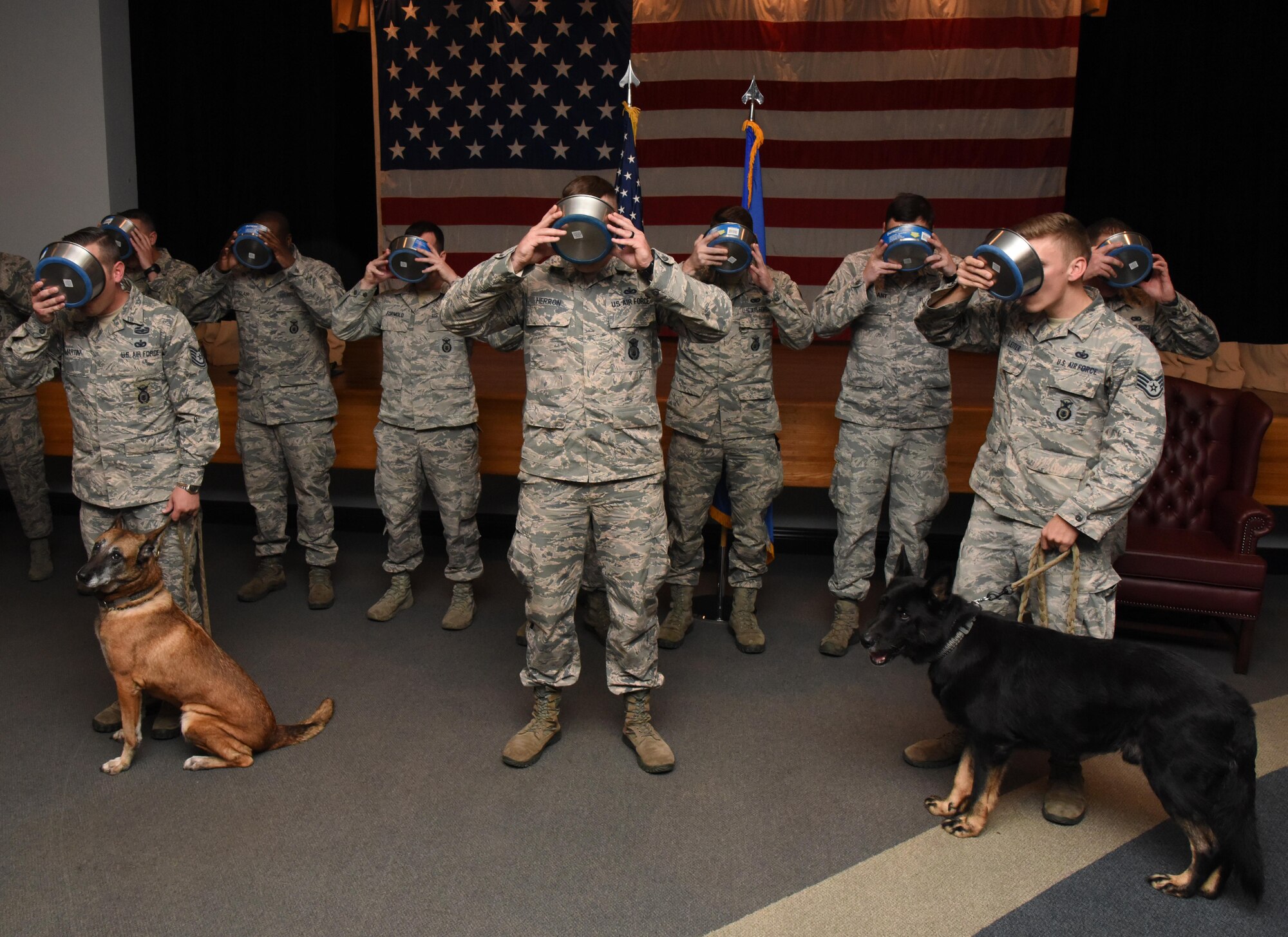 Members of the 81st Security Forces Squadron drink a toast from dog food bowls to Densy and Ares, 81st SFS military working dogs, during their retirement ceremony at the Keesler Medical Center Don Wylie Auditorium Dec. 2, 2016, on Keesler Air Force Base, Miss. They served more than 17 years combined in the Air Force. (U.S. Air Force photo by Kemberly Groue)