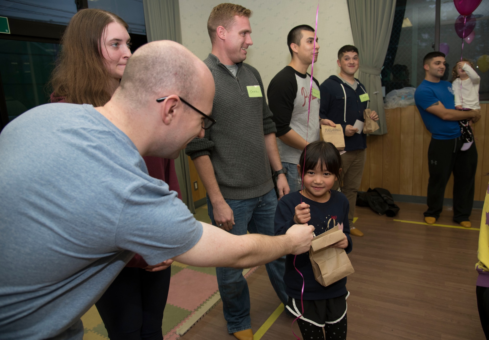 U.S. Air Force Airman 1st Class Ryan Friel, a 35th Communications Squadron cyber transport technician, hands a balloon to a Japanese national during a Jido-kan class at Okamisawa Grade School, Misawa City, Japan, Nov. 22, 2016. During the class, Airmen go over songs, reading and studying flashcards in English with the grade schoolers. (U.S. Air Force photo by Airman 1st Class Sadie Colbert)