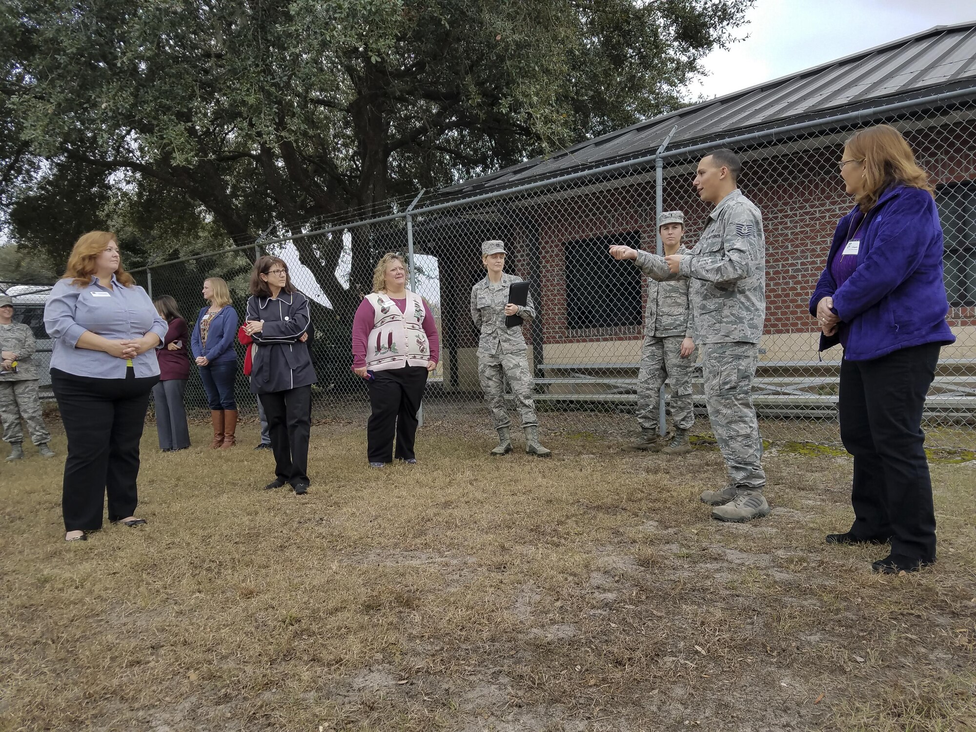 Joint Base Charleston spouses listen to Tech. Sgt. Jonathan Calo, 628th Security Forces Squadron military working dog trainer, right, as they participate in a base tour of Joint Base Charleston, S.C., Dec. 5, 2016. Spouses had the opportunity to tour various mission sets across the Air Base.