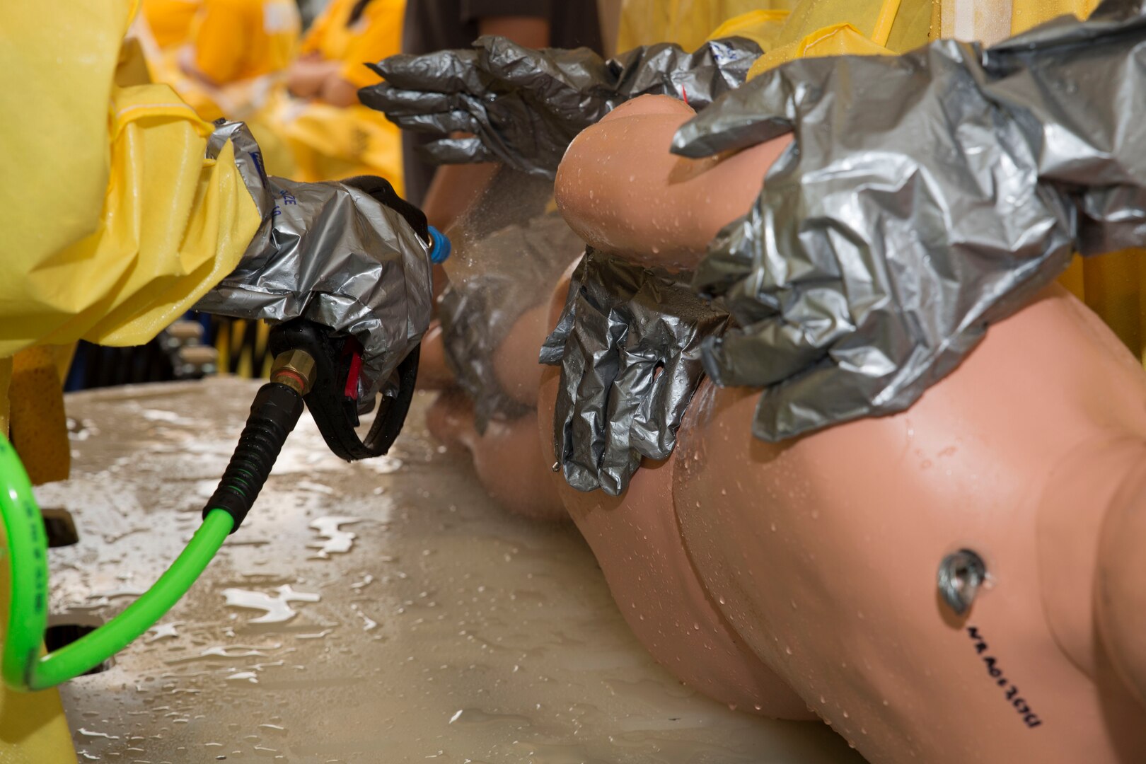 The hazardous material, or hazmat, team with the Robert M. Casey Medical and Dental Clinic washes the back of their mock patient during decontamination training at Marine Corps Air Station Iwakuni, Japan, Dec. 1, 2016. The team is given patients to decontaminate. Ambulatory care patients are able to walk through the tent with instruction from the hazmat team. Unconscious patients require help from the team to wash off all contaminants.  (U.S. Marine photo by Lance Cpl. Gabriela Garcia-Herrera)