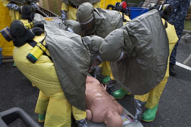 The hazardous material, or hazmat, team with the Robert M. Casey Medical and Dental Clinic place a simulated patient on the ground during decontamination training at Marine Corps Air Station Iwakuni, Japan, Dec. 1, 2016 Ambulatory care patients are able to walk through the tent with instruction from the hazmat team. Unconscious patients require help from the team to wash off all contaminants. (U.S. Marine photo by Lance Cpl. Gabriela Garcia-Herrera)