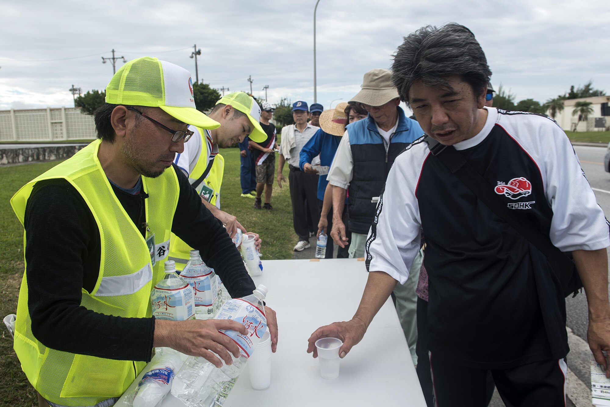 Residents of Chatan Town grab cups of water as they make their way through Kadena Air Base, Japan, as part of a bilateral tsunami evacuation exercise Dec. 4, 2016. Preparation is invaluable when the need to respond to a disaster arises and this sort of exercise allows people to see what would happen in a real-world situation. (U.S. Air Force photo by Airman 1st Class Corey Pettis/Released)