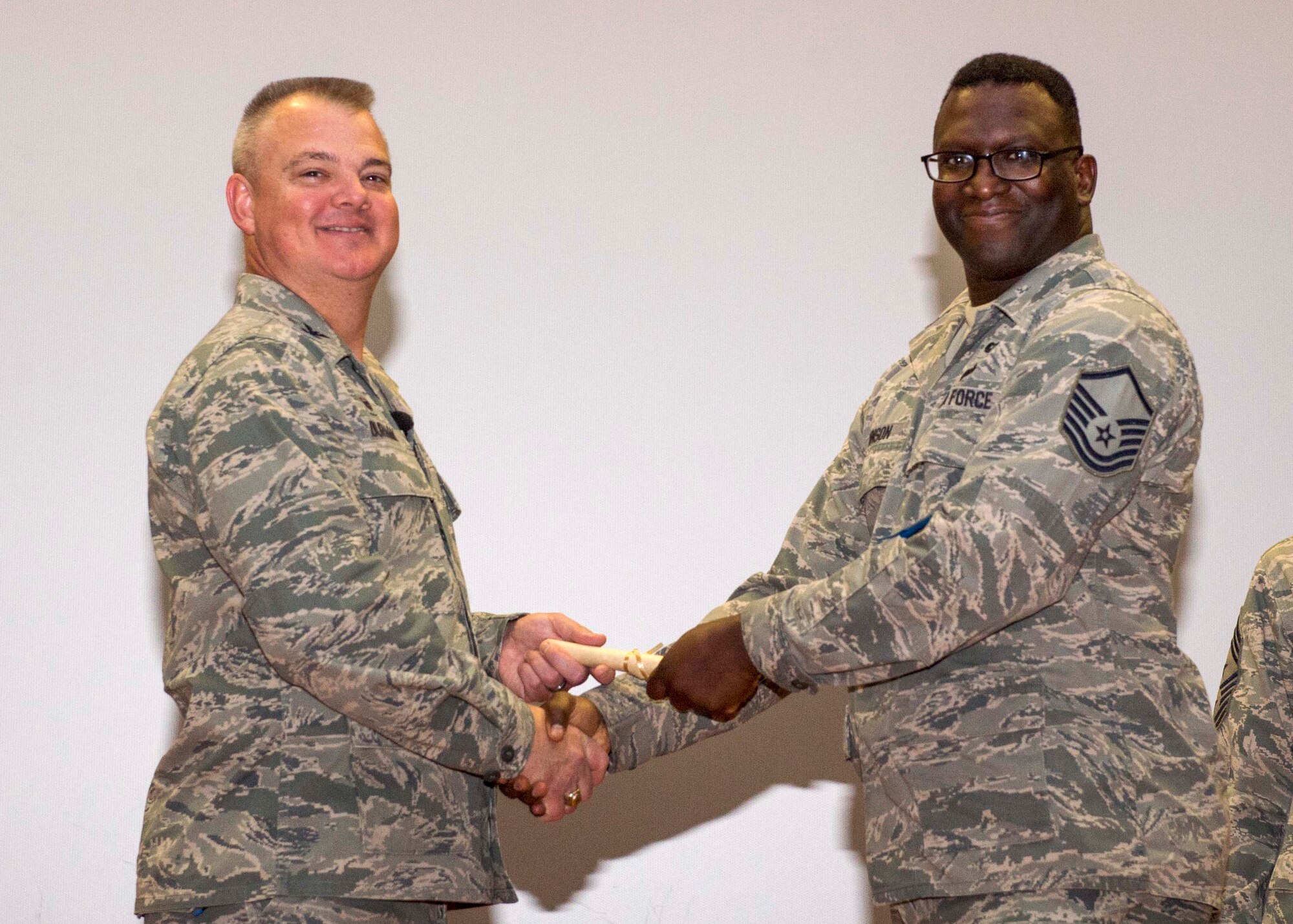 Master Sgt. Darnell Johnson, 512th Aircraft Maintenance Squadron, shakes hands with Col. Scott D. Durham, 512th Airlift Wing commander, during the wing's Community College of the Air Force graduation ceremony Dec. 3, 2016, Dover Air Force Base, Del. The wing surpassed their goal of awarding 100 CCAF degrees during the year and awarded 109 degrees. (U.S. Air Force Photo/Staff Sgt. Renee Jackson)