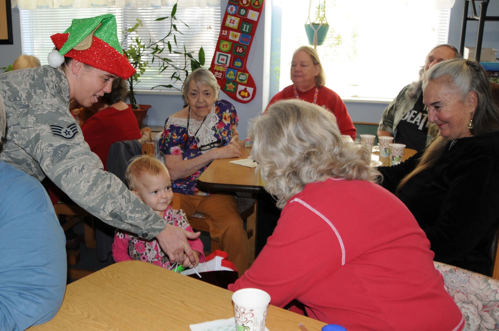 Staff Sgt. Amber Palama, 924th Fighter Group aircrew flight equipment, helps Ani Hugo, 2, hand out presents to the residents of the Western Winds Apartments, December 3, 2016. The 924th adopted the senior living community for Christmas and threw them a holiday party. Hugo is the daughter of TSgt Dale Hugo, 924th Maintenance Squadron plans and scheduling documentation specialist. (U.S. Air Force photo by Tech. Sgt. Courtney Richardson)