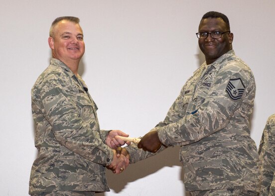 Master Sgt. Darnell Johnson, 512th Aircraft Maintenance Squadron, shakes hands with Col. Scott D. Durham, 512th Airlift Wing commander, during the wing's Community College of the Air Force graduation ceremony Dec. 3, 2016, Dover Air Force Base, Del. The wing surpassed their goal of awarding 100 CCAF degrees during the year and awarded 109 degrees. (U.S. Air Force Photo/Staff Sgt. Renee Jackson)