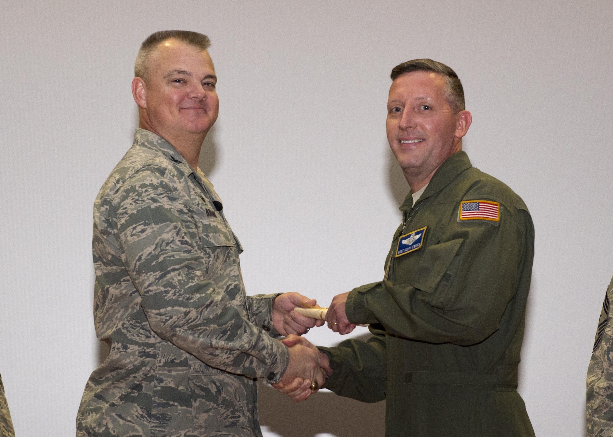 Master Sgt. Scott O’Brien, 709th Airlift Squadron, shakes hands with Col. Scott D. Durham, 512th Airlift Wing commander, during the wing's Community College of the Air Force graduation ceremony, Dec. 3, 2016, Dover Air Force Base, Del. The wing surpassed their goal of awarding 100 CCAF degrees during the year and awarded 109 degrees. (U.S. Air Force Photo/Staff Sgt. Renee Jackson)