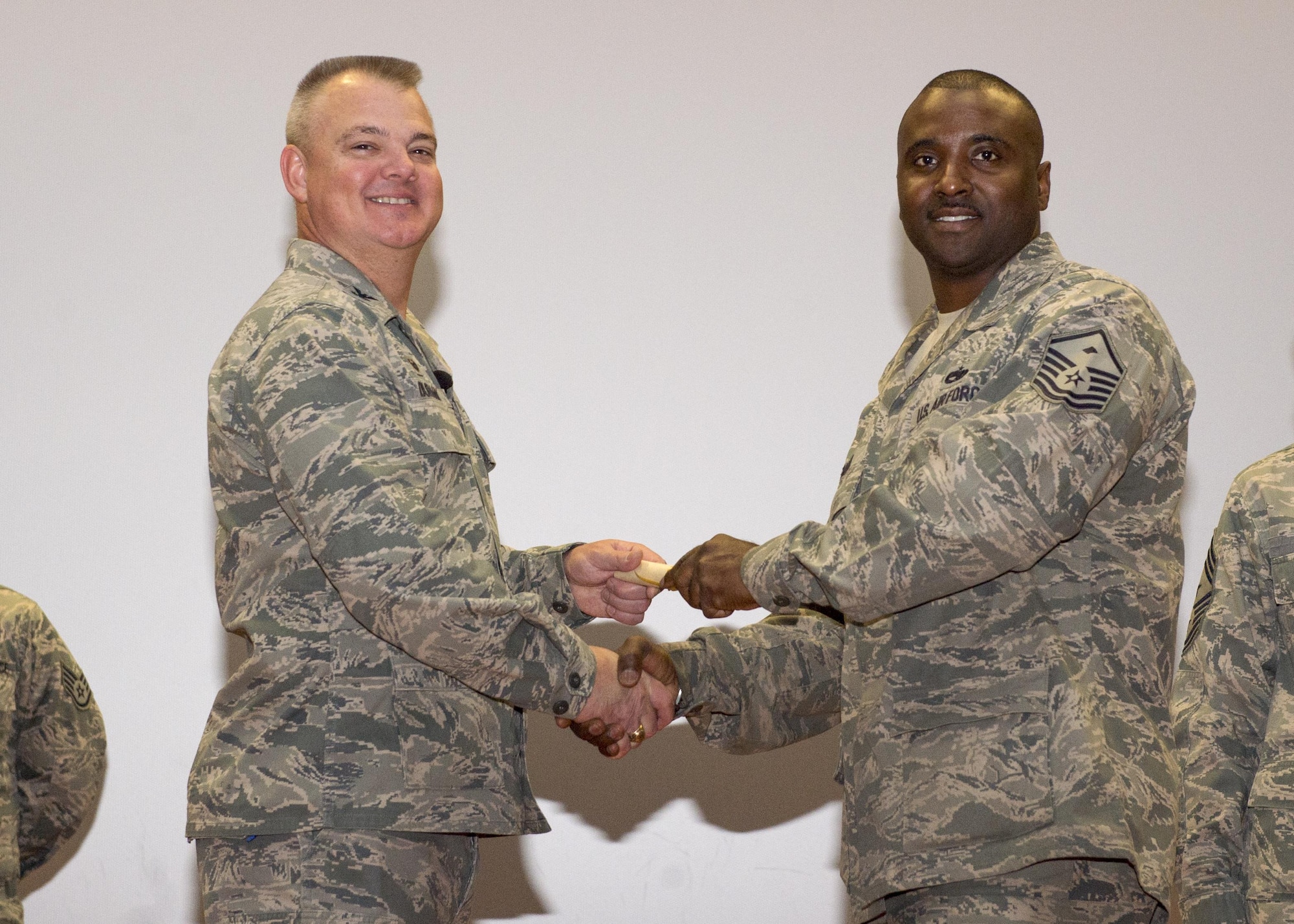 Master Sgt. Kuentin Smart, 46th Aerial Port Squadron, shakes hands with Col. Scott D. Durham, 512th AW commander, during the wing's Community College of the Air Force graduation ceremony, Dec. 3, 2016, Dover Air Force Base, Del. The wing surpassed their goal of awarding 100 CCAF degrees during the year and awarded 109 degrees. (U.S. Air Force Photo/Staff Sgt. Renee Jackson)