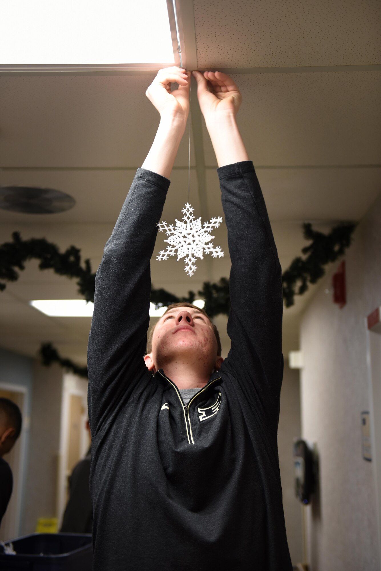 Airman 1st Class Aaron Longgood, 92nd Logistics Readiness Squadron fuels distribution operator, hangs paper snowflakes from the ceiling during the 92nd LRS volunteer event Dec. 2, 2016, at the Spokane Veterans Home. The main goal for volunteers is to give veterans, especially those who do not have families, a happy holiday season. (U.S. Air Force photo/ Airman 1st Class Sean Campbell)