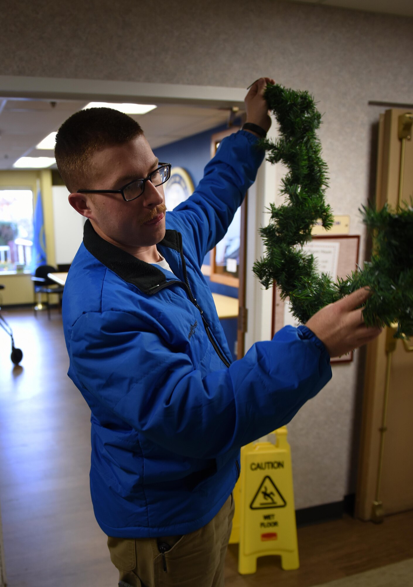 Senior Airman Auston Reeves, 92nd Logistics Readiness Squadron vehicle operations journeyman, hangs garland during the 92nd LRS volunteer event Dec. 2, 2016, at the Spokane Veterans Home in Spokane. For 14 consecutive years, Airmen have taken the time to set the holiday vibe for veterans and spread holiday cheer by setting up decorations. (U.S. Air Force photo/ Airman 1st Class Sean Campbell)
