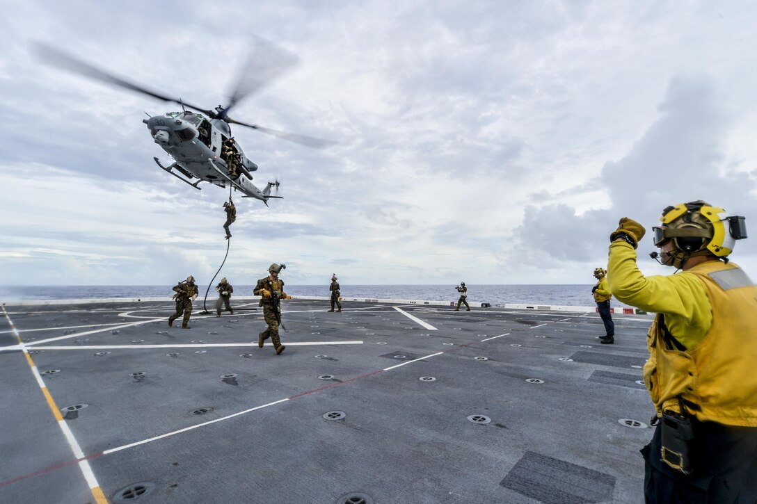 Navy Petty Officer 2nd Class Ramiro Alvarez directs a UH-1 Huey helicopter as Marines repel during fast-rope training aboard the USS Somerset in the Pacific Ocean, Nov. 2, 2016. The Somerset is operating in the U.S. 7th Fleet area of operations with the embarked 11th Marine Expeditionary Unit to support security and stability in the Indo-Asia-Pacific region. Navy photo by Petty Officer 3rd Class Amanda Chavez