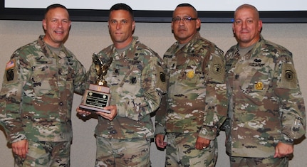 Maj. Gen. Jeffrey J. Snow (left), commander, U.S. Army Recruiting Command, presents the U.S. Army 
Medical Recruiting Brigade’s “Top Recruiting Battalion of Excellence” award to (second from left) Lt. Col. Michael T. Peacock, 5th Medical Recruiting Brigade commander, and Command Sgt. Maj. Jesse Castellano Jr. (second from right). With them is U.S. Army Recruiting Command Sgt. Maj. Anthony T. Stoneburg (right).   
