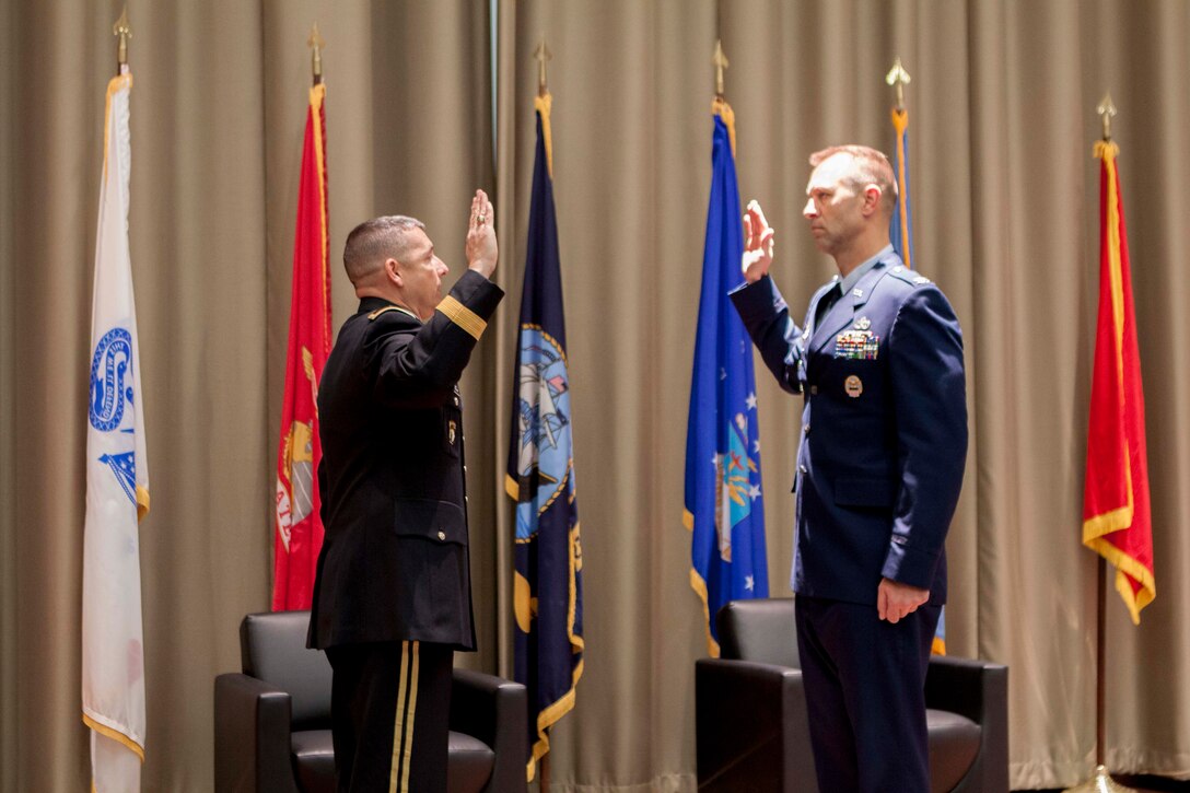 Air Force Lt Col Mike Davis recites the oath of office to DLA Distribution commanding general Army Brig. Gen. John Laskodi as his last action before assuming the rank of Colonel.  