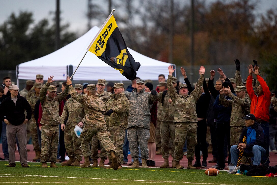 U.S. Army Lt. Col. Yukio Kuniyuki, 344th Military Intelligence Battalion Commander, runs down the sideline with a flag as fellow Soldiers attempt the wave during the Army vs. Navy football game at the Mathis Fitness Center football field on Goodfellow Air Force Base, Texas, Dec. 2, 2016. The Army beat the Navy with a final score of 21 to 7. (U.S. Air Force photo by Senior Airman Devin Boyer/Released)