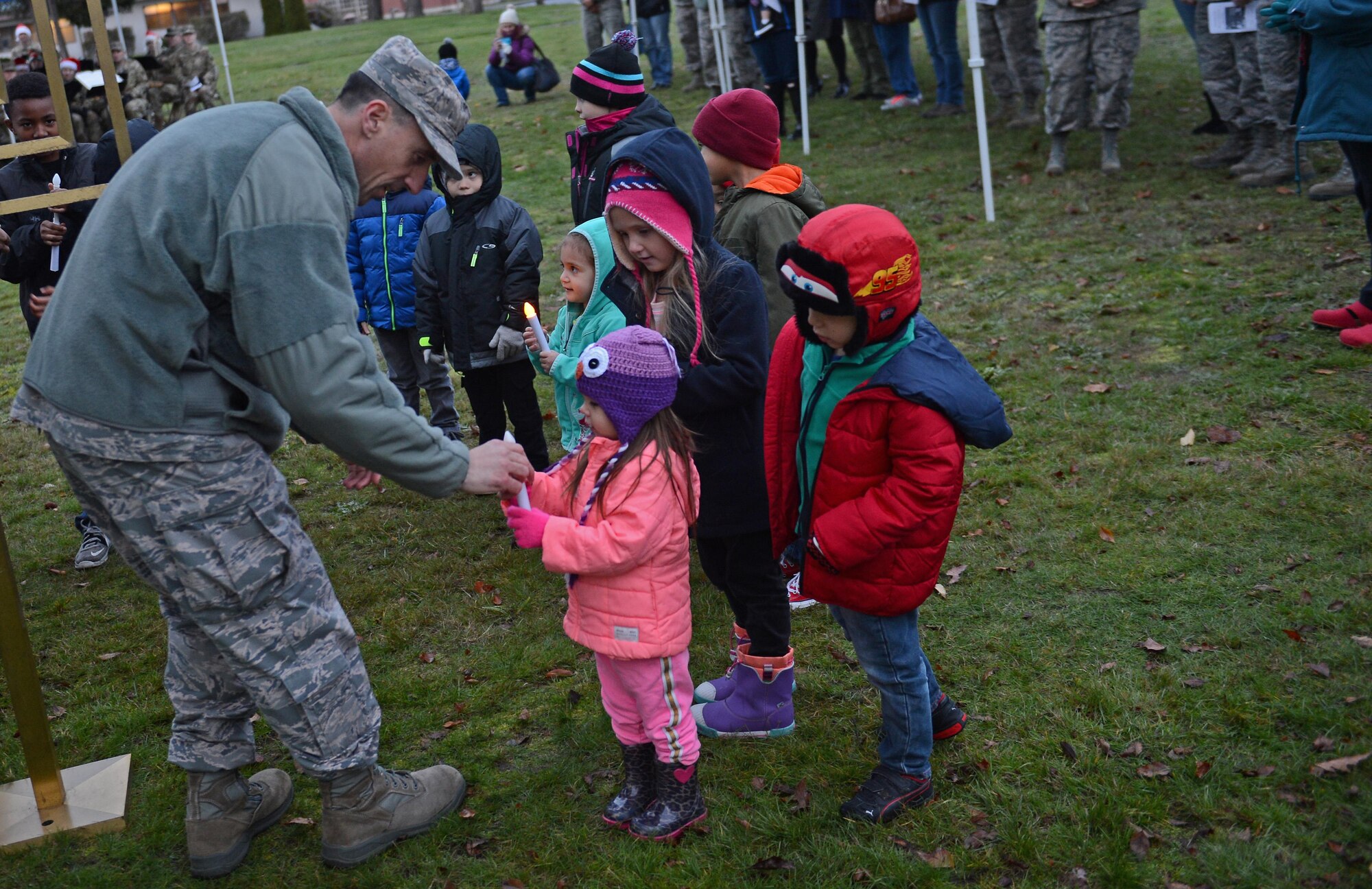 Col. Leonard Kosinski, 62nd Airlift Wing commander, helps children light candles for the Menorah during the McChord Field Annual Tree Lighting Ceremony Dec. 5, 2016 at Joint Base Lewis-McChord, Wash. Along with the Menorah, a Christmas tree was also lit during the ceremony. (U.S. Air Force photo/Senior Airman Divine Cox)