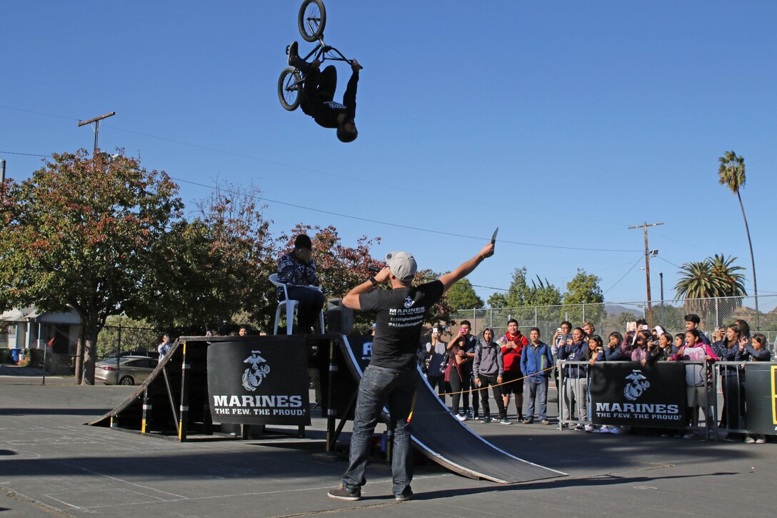 BMX rider Mykel Larrin performs a flip over Franklin High School Principal Regina Marquez-Martinez at Franklin High School in Los Angeles, Calif., Dec. 2, 2016. The ASA High School tour is a high-energy action sports circuit that visits cities across the United States supporting the Anti-Defamation League’s No Place for Hate campaign and the campaign for Tobacco-Free Kids. (U.S. Marine Corps photo by Staff Sgt. Alicia R. Leaders/Released)
