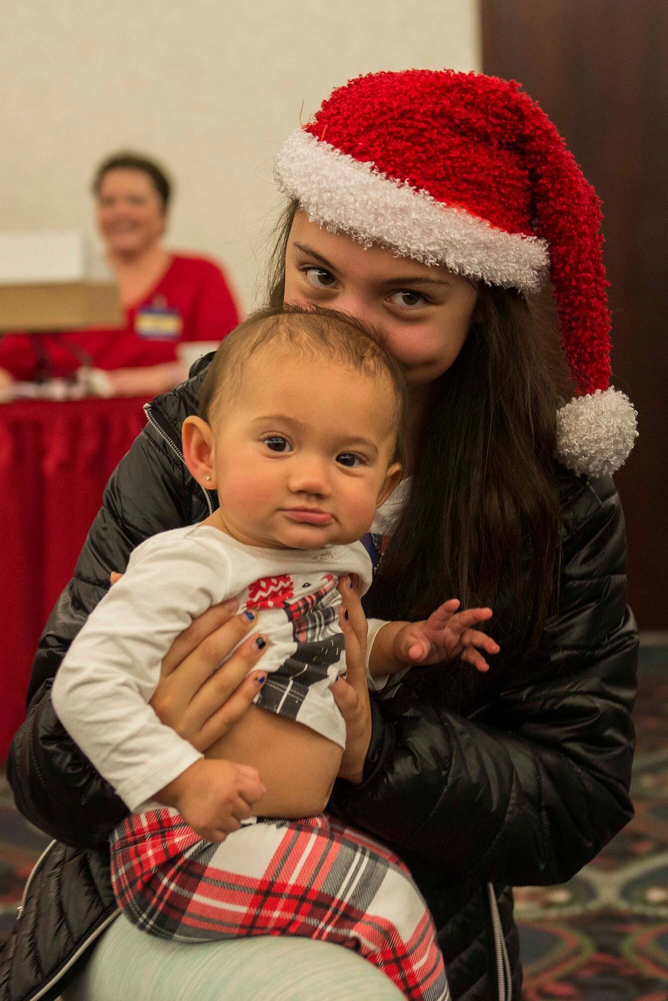 A child holds her sister at the Holiday Party and Tree Lighting at Scott Air Force Base, Ill., Nov. 30, 2016. Many children were dressed in festive clothes and participated in holiday crafts. (U.S. Air Force photo by Senior Airman Megan Friedl)