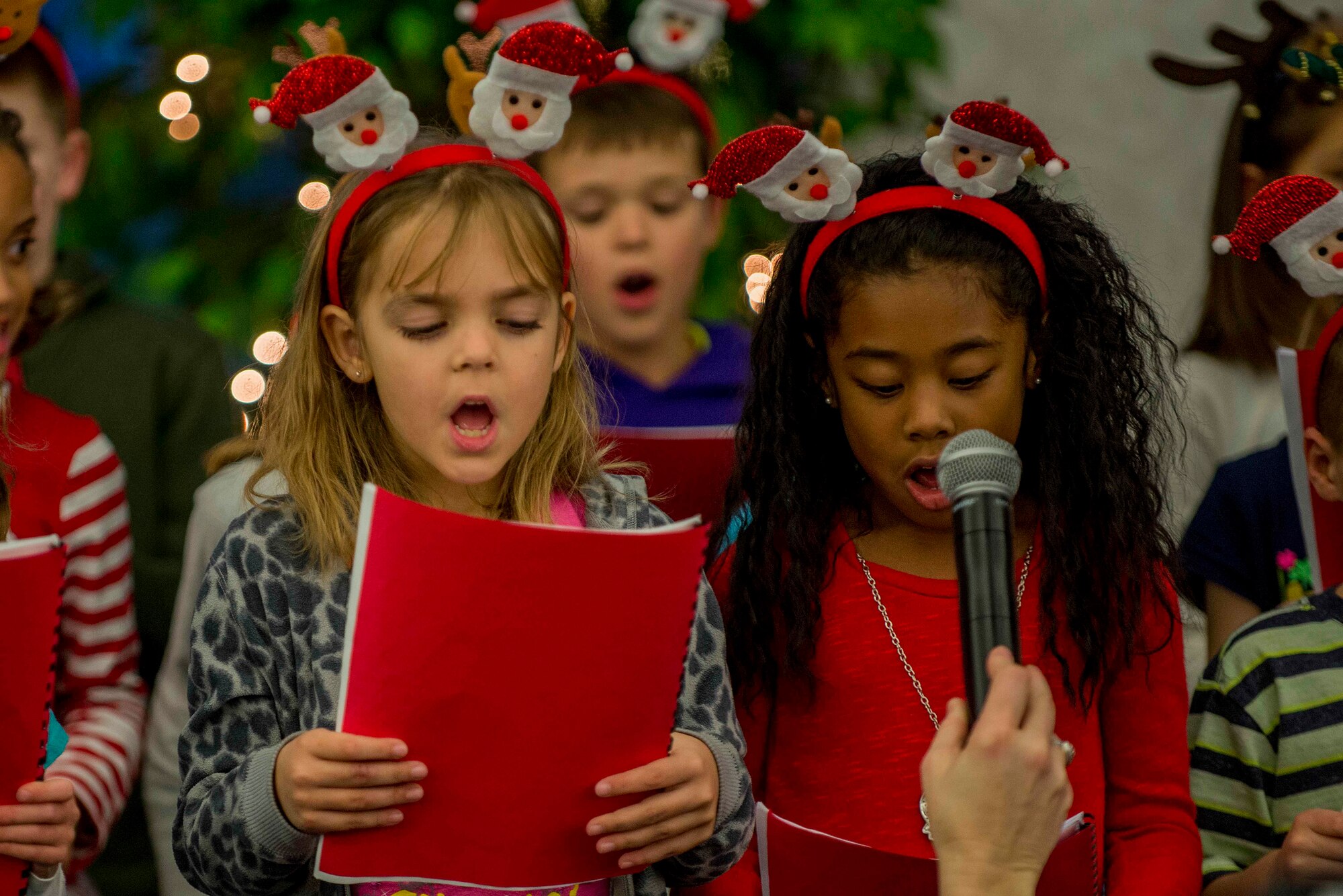Children from the Scott AFB Youth Programs Choir sing Holiday songs at the Holiday Party and Tree Lighting at Scott Air Force Base, Ill., Nov. 30, 2016. Children sang many traditional Christmas songs during the event. (U.S. Air Force photo by Senior Airman Josh Eikren)