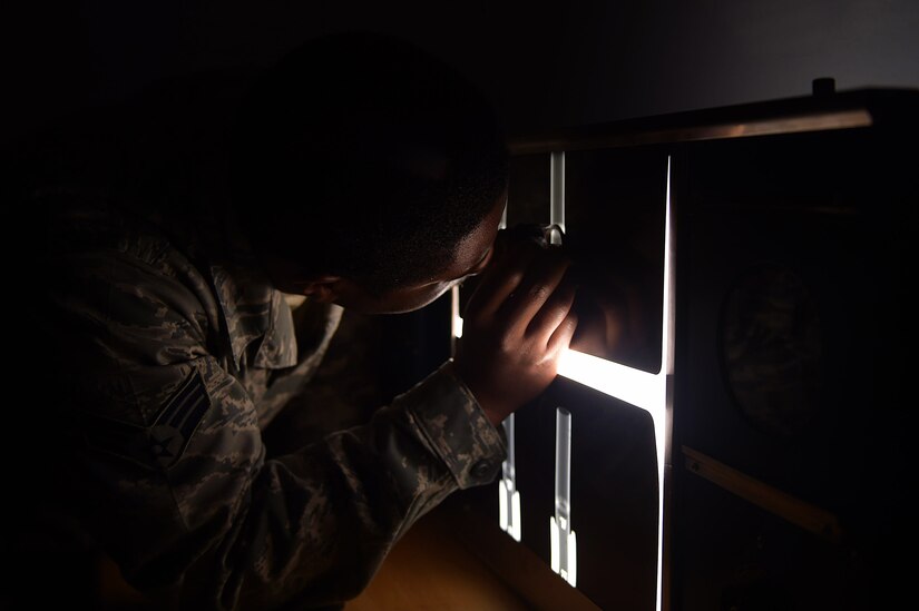 U.S Air Force Senior Airman Rickey Godette, 1st Maintenance Squadron Nondestructive Inspection journeyman, reviews film at Joint Base Langley-Eustis, Va., Dec. 5, 2016. The X-ray image is used to look for foreign object debris that could be inside of the aircraft. (U.S. Air Force photo by Senior Airman Kimberly Nagle)