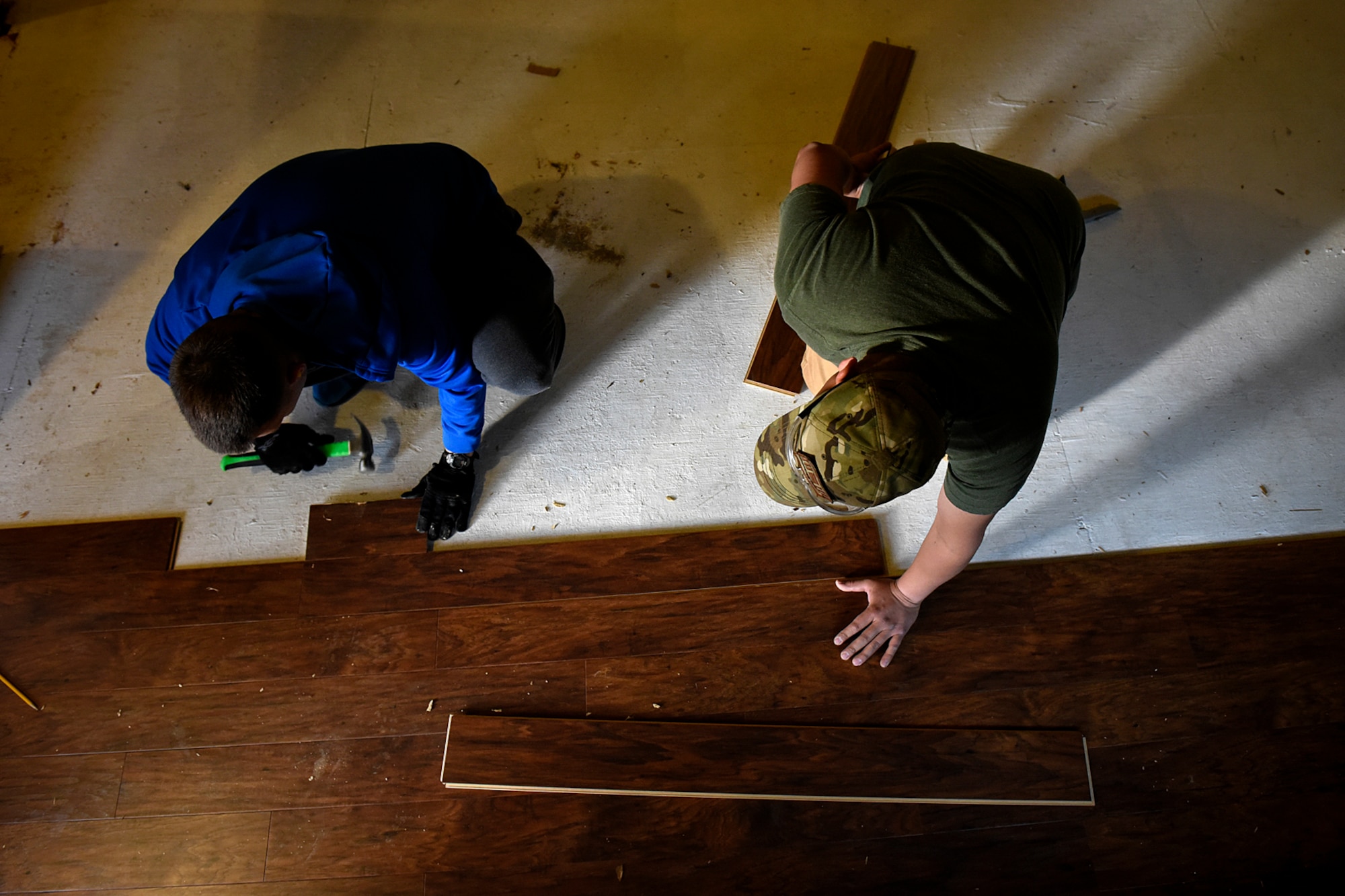 COLORADO SPRINGS, Colo. – Staff Sgt. Robert Helton and Senior Airman Guillermo Loaiza-Martinez, 21st Civil Engineer Squadron structures shop at Peterson Air Force Base, Colo., work together to install flooring in a fellow Airman’s home in Colorado Springs, Nov. 5, 2016. Volunteers from around base helped their wingman so he could focus on his family and healing, rather than the logistics of repairing the flooring. (U.S. Air Force photo by Senior Airman Rose Gudex)