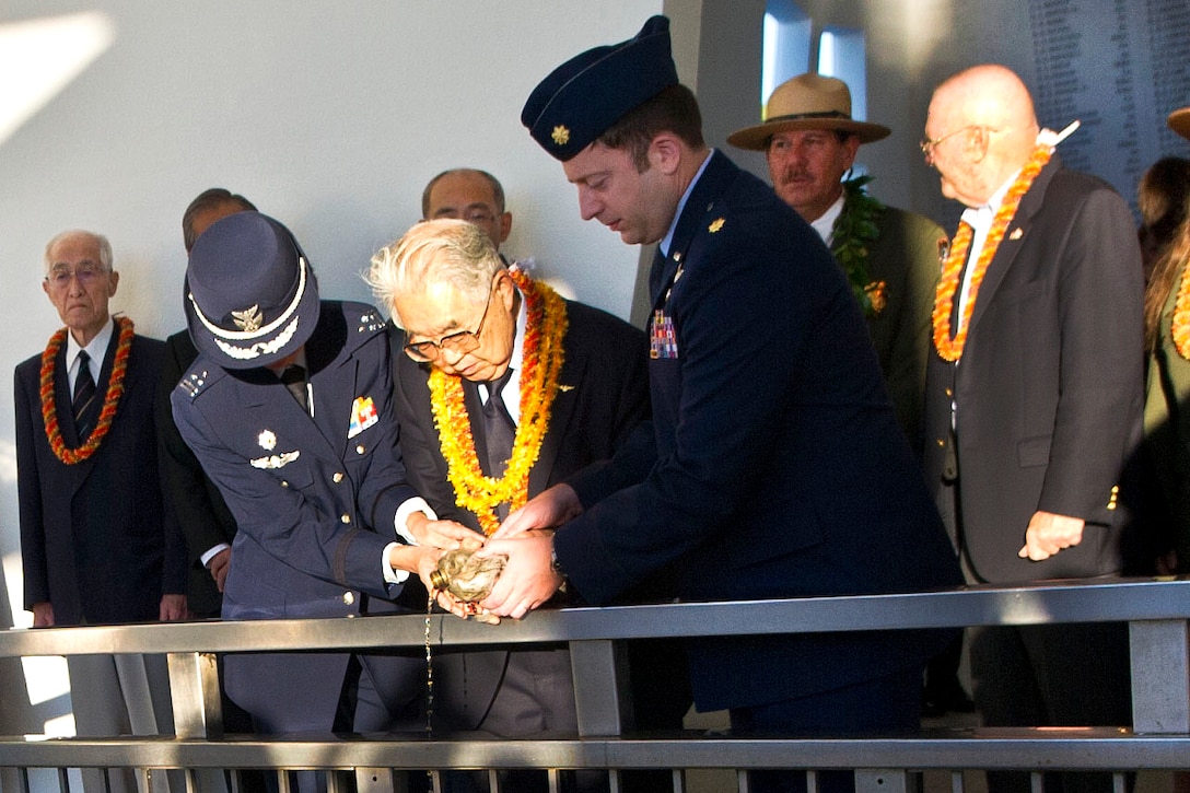 Dr. Hiroya Sugano, center, the caretaker of the Blackened Canteen tradition, a U.S. airman and a member of the Japanese military pour bourbon whiskey into the hallowed waters at the USS Arizona Memorial in Pearl Harbor, Hawaii, Dec. 6, 2016. The whiskey is a peace offering. The vessel is a World War II-era canteen recovered at a crash site where two American bombers collided after a deadly raid on Shizuoka, Japan, June 19, 1945. The aircrews and 2,000 Japanese citizens were killed in the air raid. Sugano is the director general of the Zero Fighter Admirers Club. DoD photo by Lisa Ferdinando