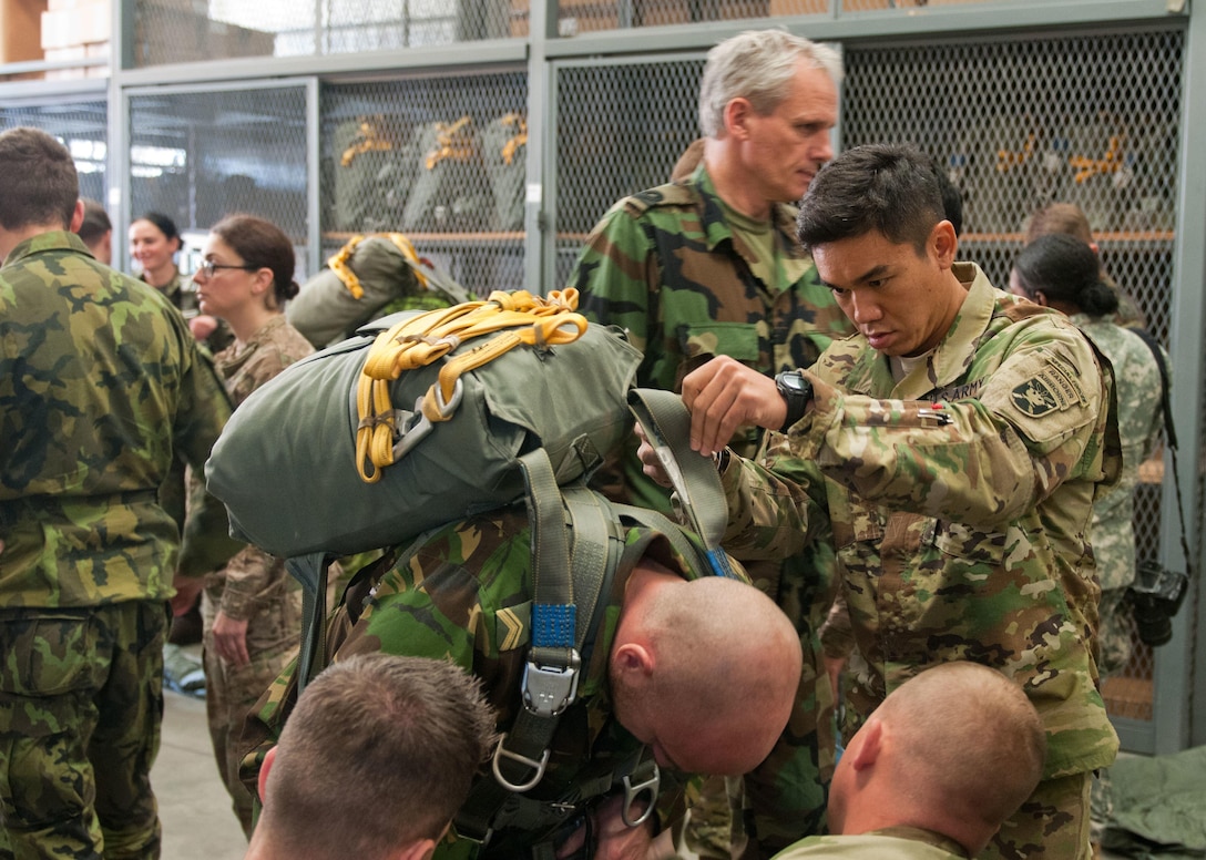 Army Sfc. Phouphadith Voravong, representing the HHC, USAJFKSWCS, assists a soldier from the Netherlands with donning MC6 main parachute in preparation for Operation Toy Drop XIX.  Safety is the top priority for Operation Toy Drop. All jumpmasters, American and foreign spend hours in aircraft and parachute familiarization classes so they are clear on all tactics and procedures for safe operation. (U.S. Army Reserve Photo by Sgt. Darryl Montgomery