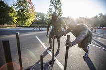 An FFI student executes a forward sled push as a part of the finisher for the day’s workout while being motivated by another student. 